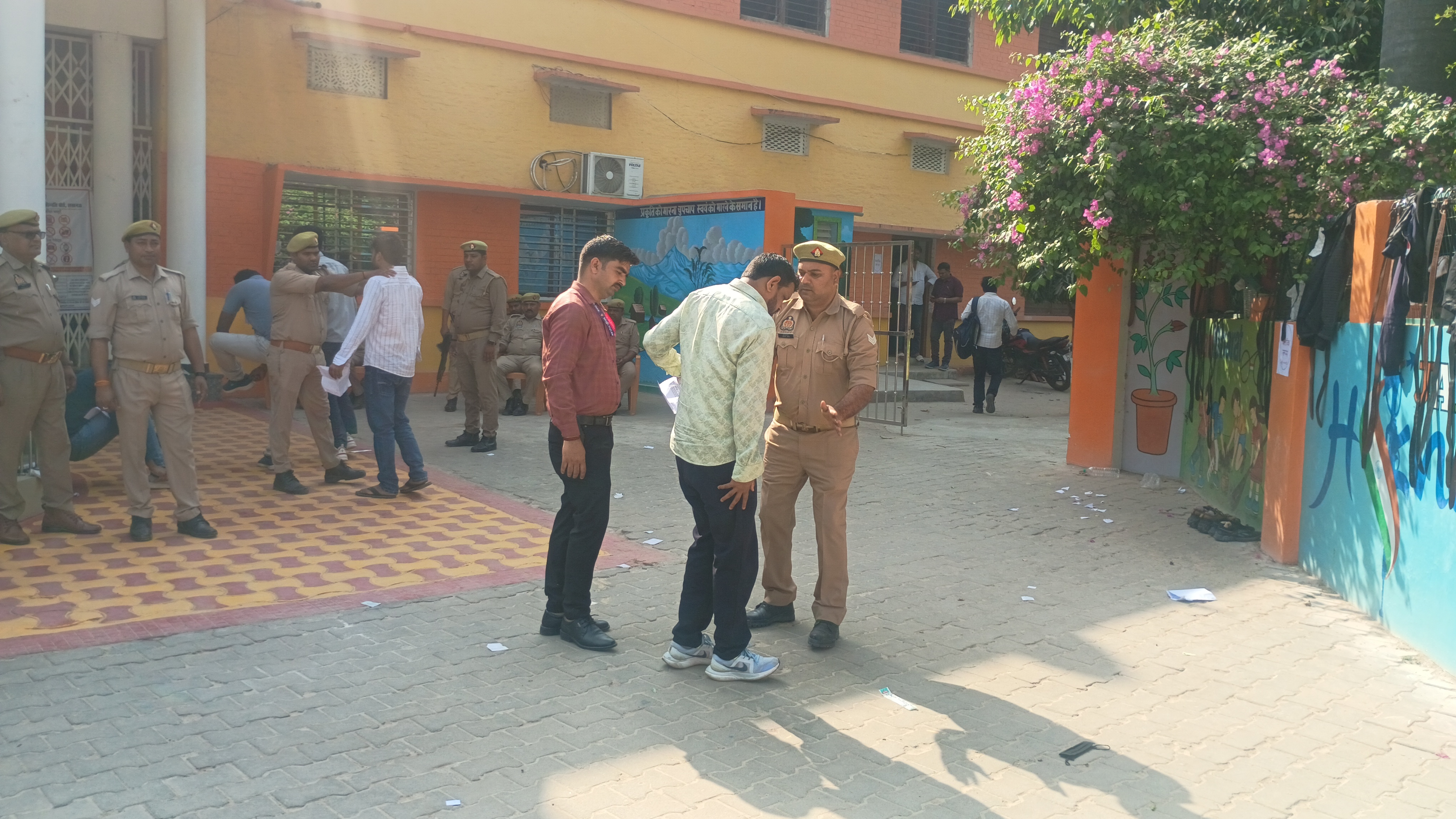 परीक्षा केंद्र पर खड़े परीक्षार्थी चेकिंग करते हुए पुलिस